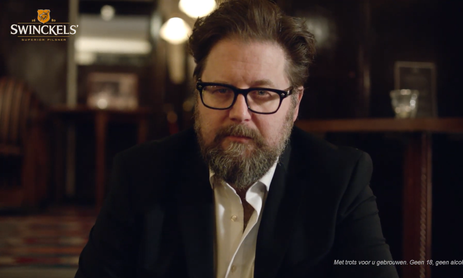 Man met baard en bril in donkere bar, met Swinckels