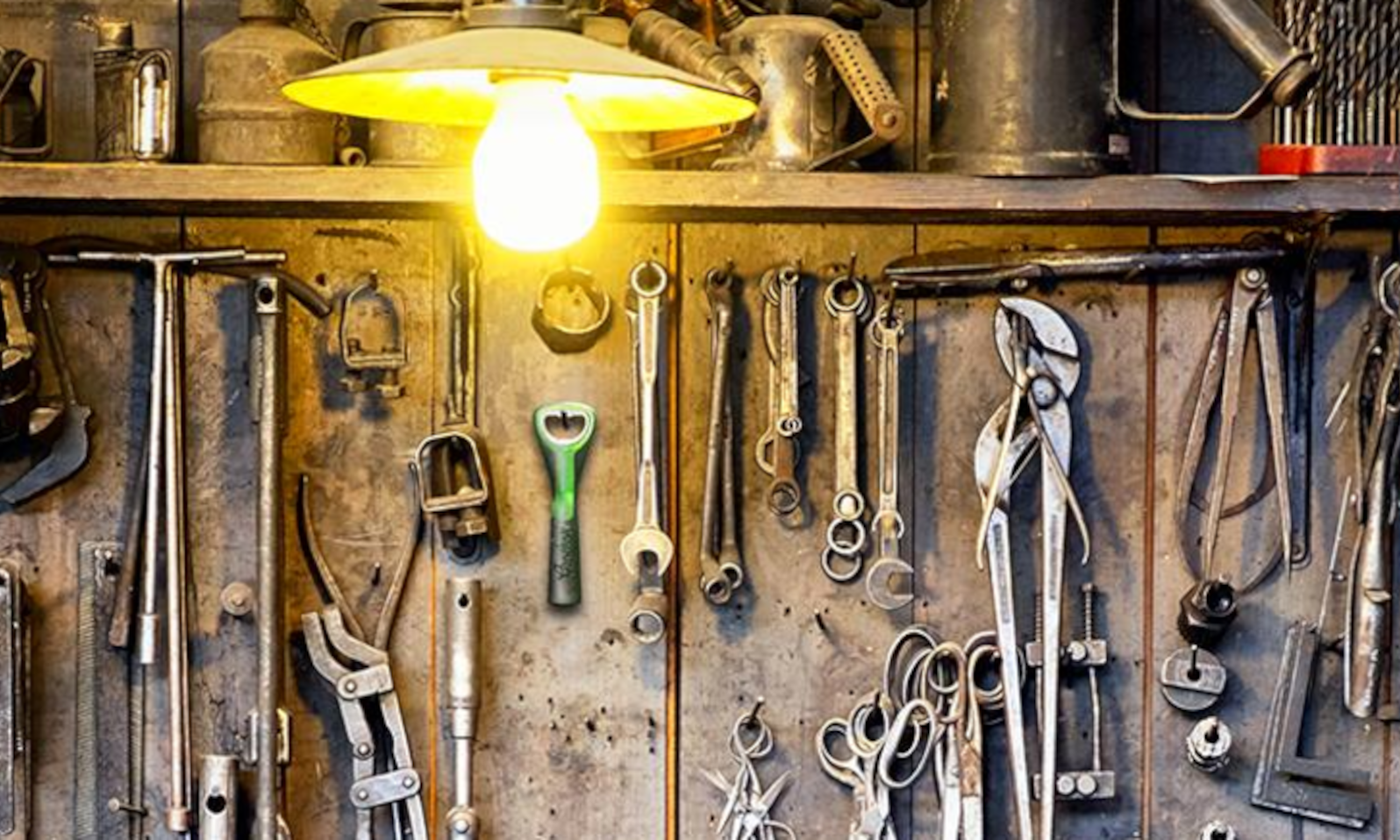 Werkbank met hangend gereedschap, verlicht door een lamp.