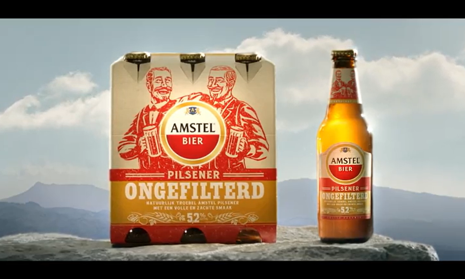 Amstel Pilsener Ongefilterd verpakking en flesje op een rots met blauwe lucht.