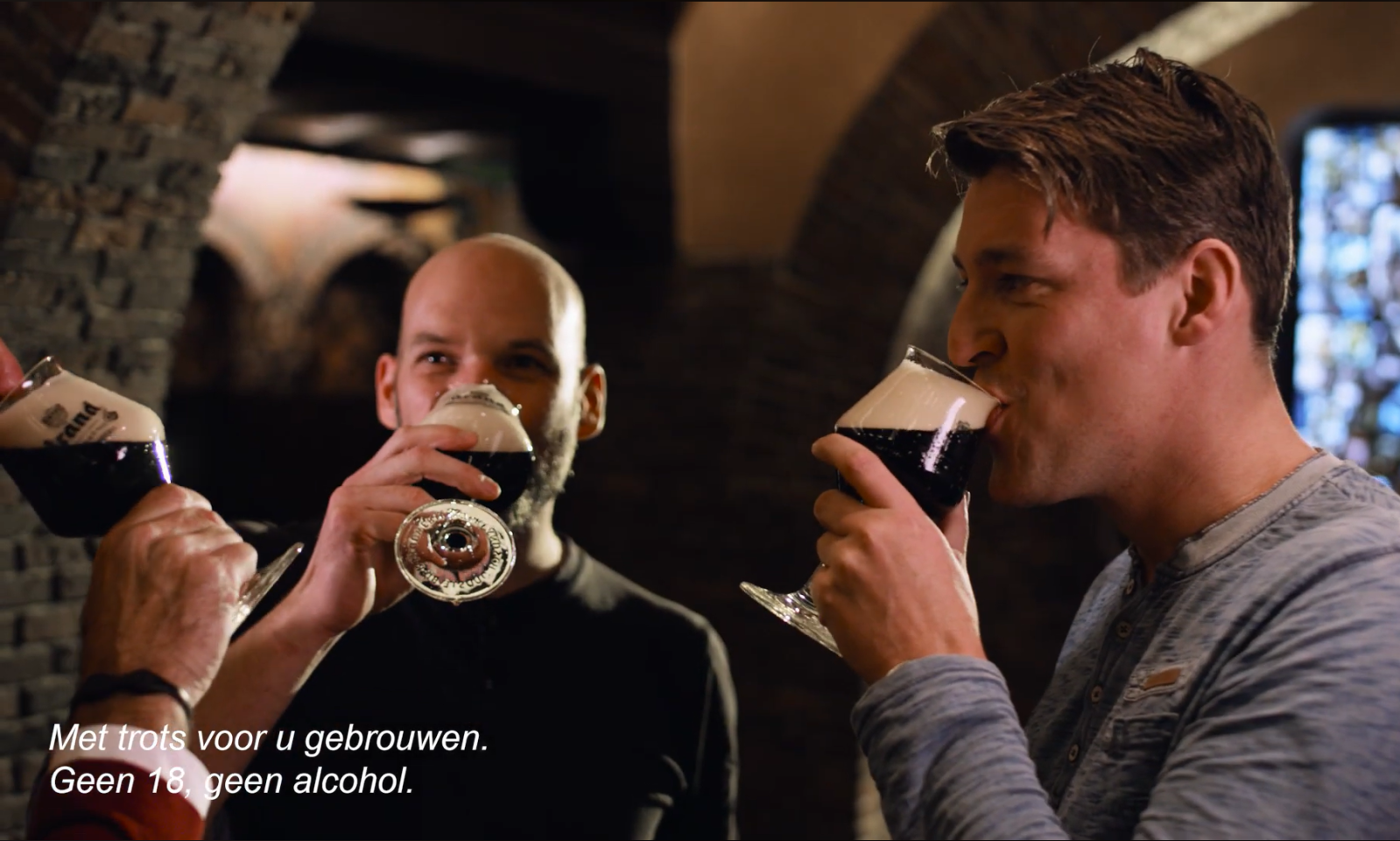 Mensen proosten met donker bier in een sfeervolle ruimte.