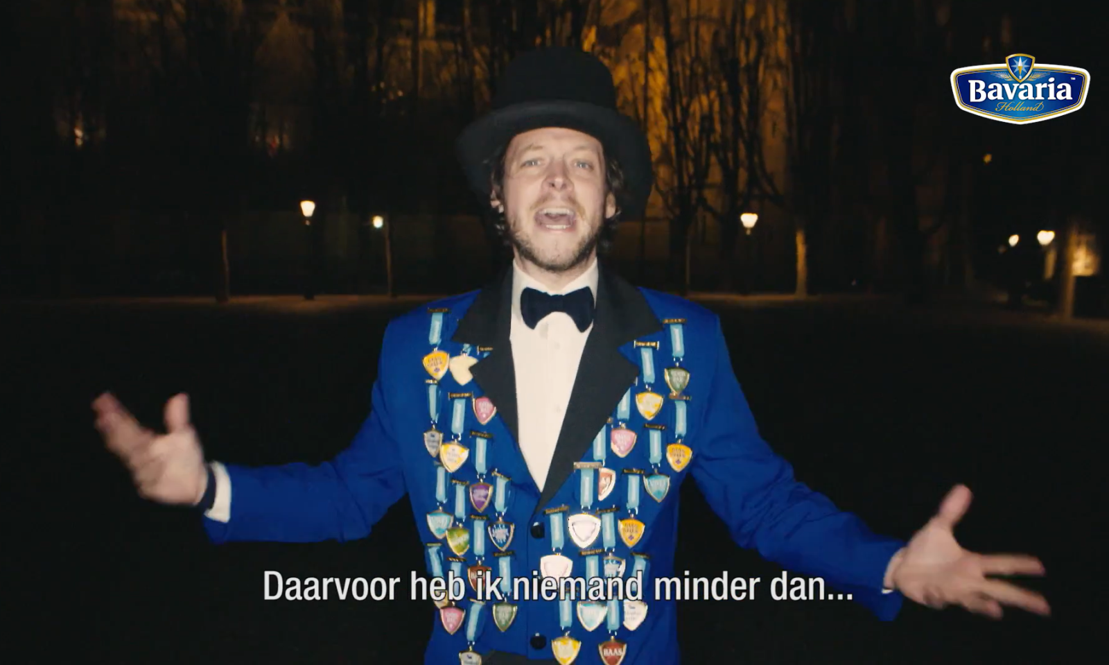 Man in blauwe jas met medailles en hoge hoed, tekst onderin beeld.