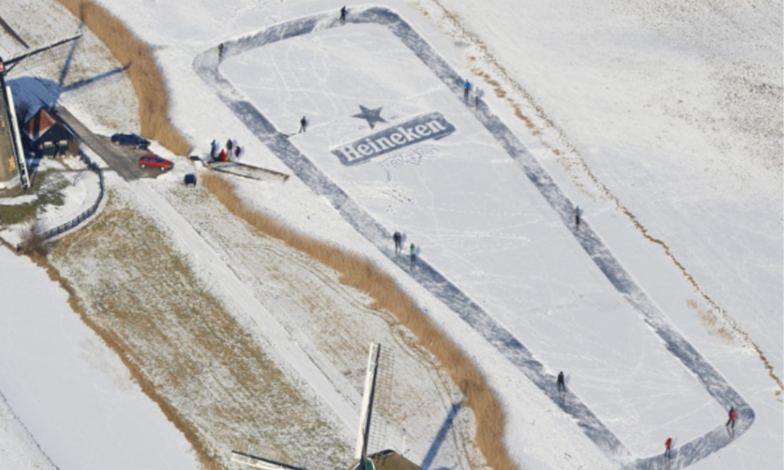 Luchtfoto van een schaatsbaan in de vorm van een Heineken-fles naast een Nederlandse molen.
