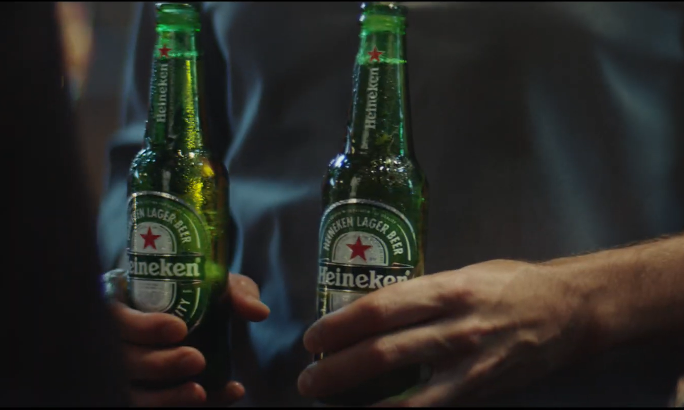 Twee Heineken bierflessen in handen van een man.