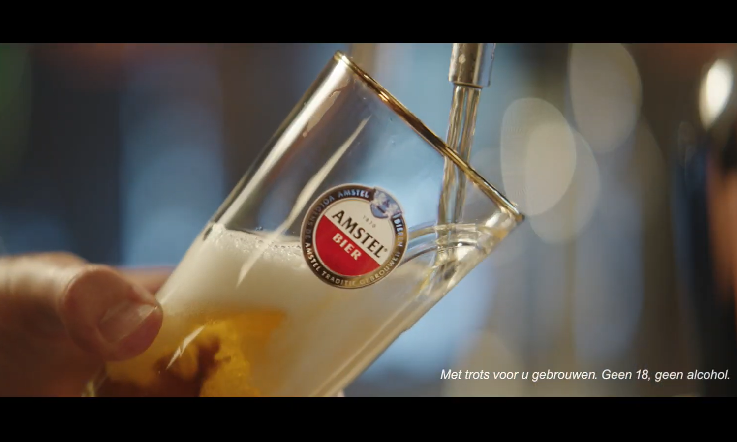 Close-up van een biertje dat wordt getapt in een glas met Amstel-logo.