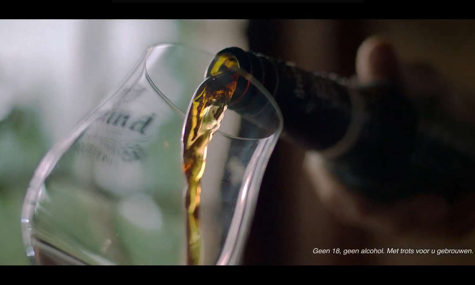 Bier wordt langzaam in een glas geschonken met tekst op de achtergrond.