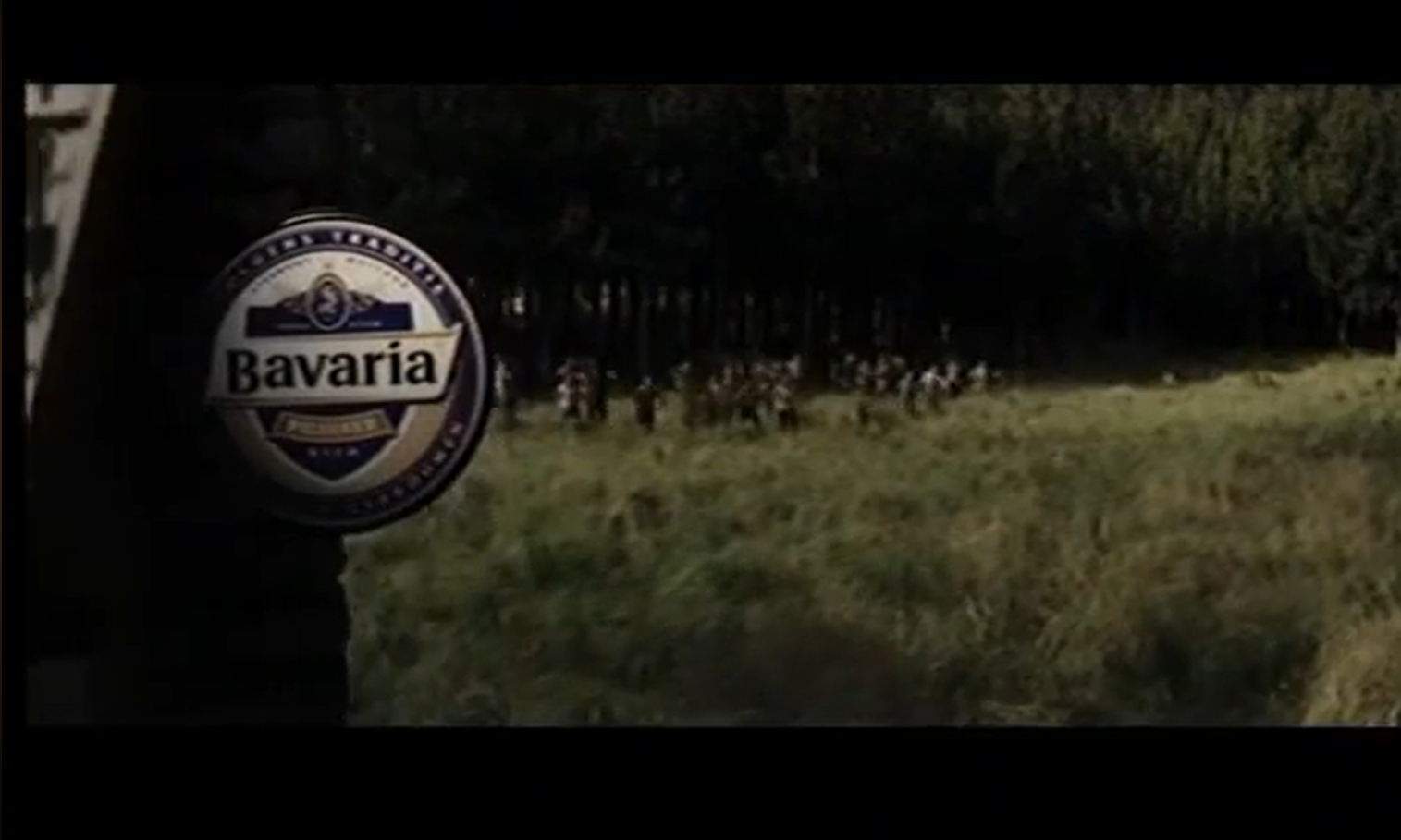 Bavaria bierfles tegen een boslandschap met mensen in de verte.