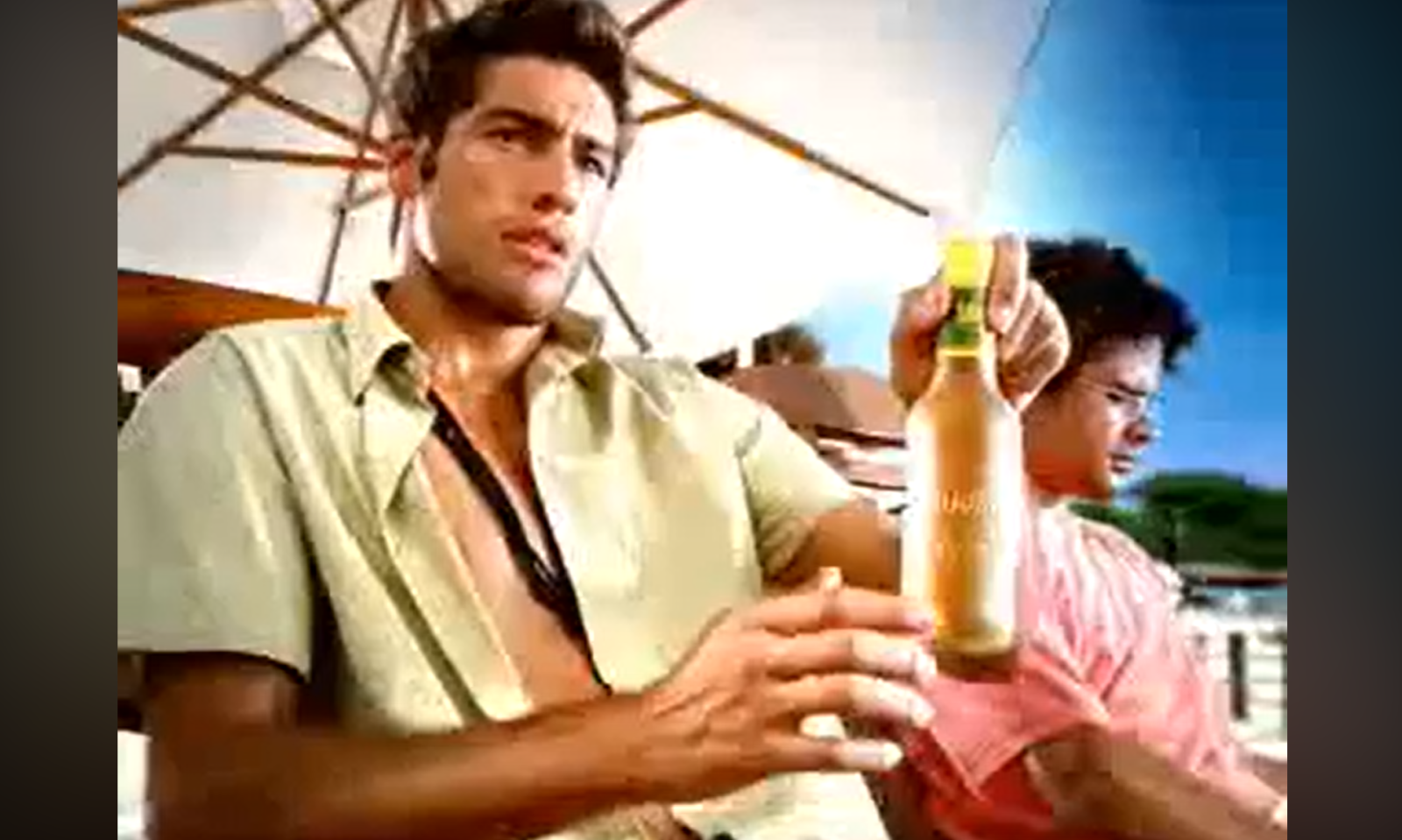 Man houdt een fles vast onder een parasol op een zomerse dag.