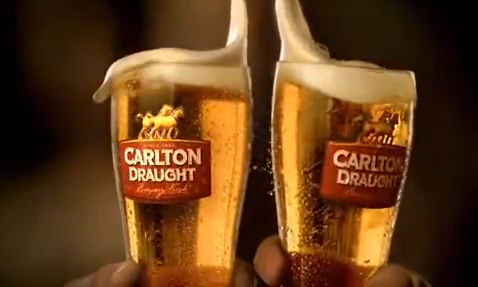 Twee bierglazen met schuimend bier en Carlton Draught logo tegen een donkere achtergrond.