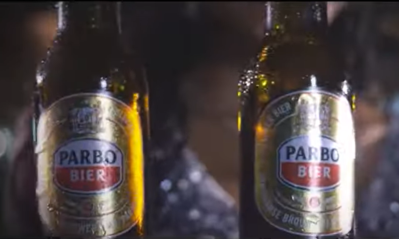 Twee flesjes Parbo Bier naast elkaar met een wazige achtergrond.