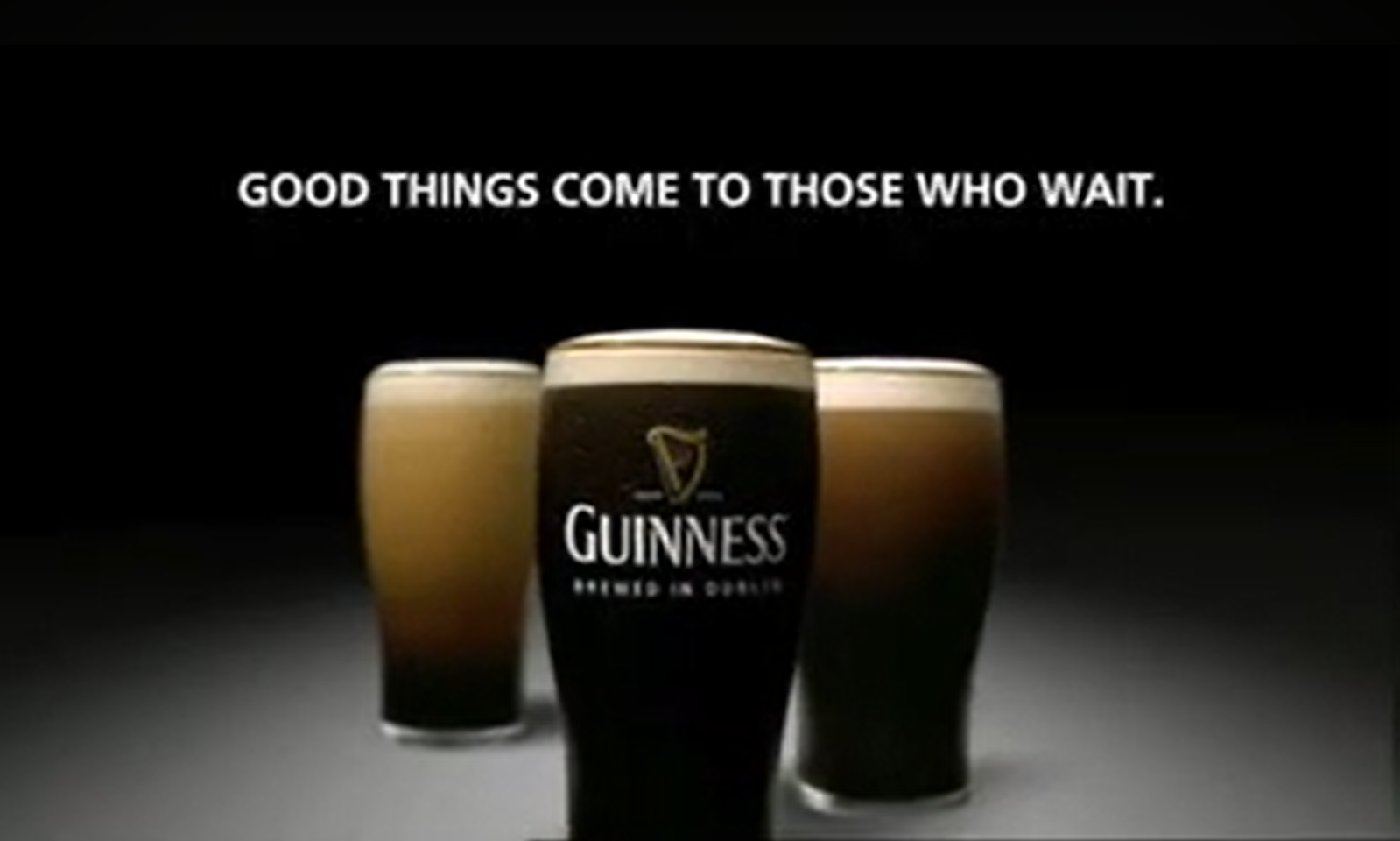 Drie volle Guinness glazen op donkere achtergrond met tekst erboven.
