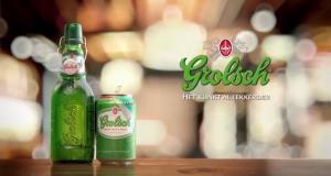 Grolsch bierfles en blik op houten tafel met vervaagde achtergrond.