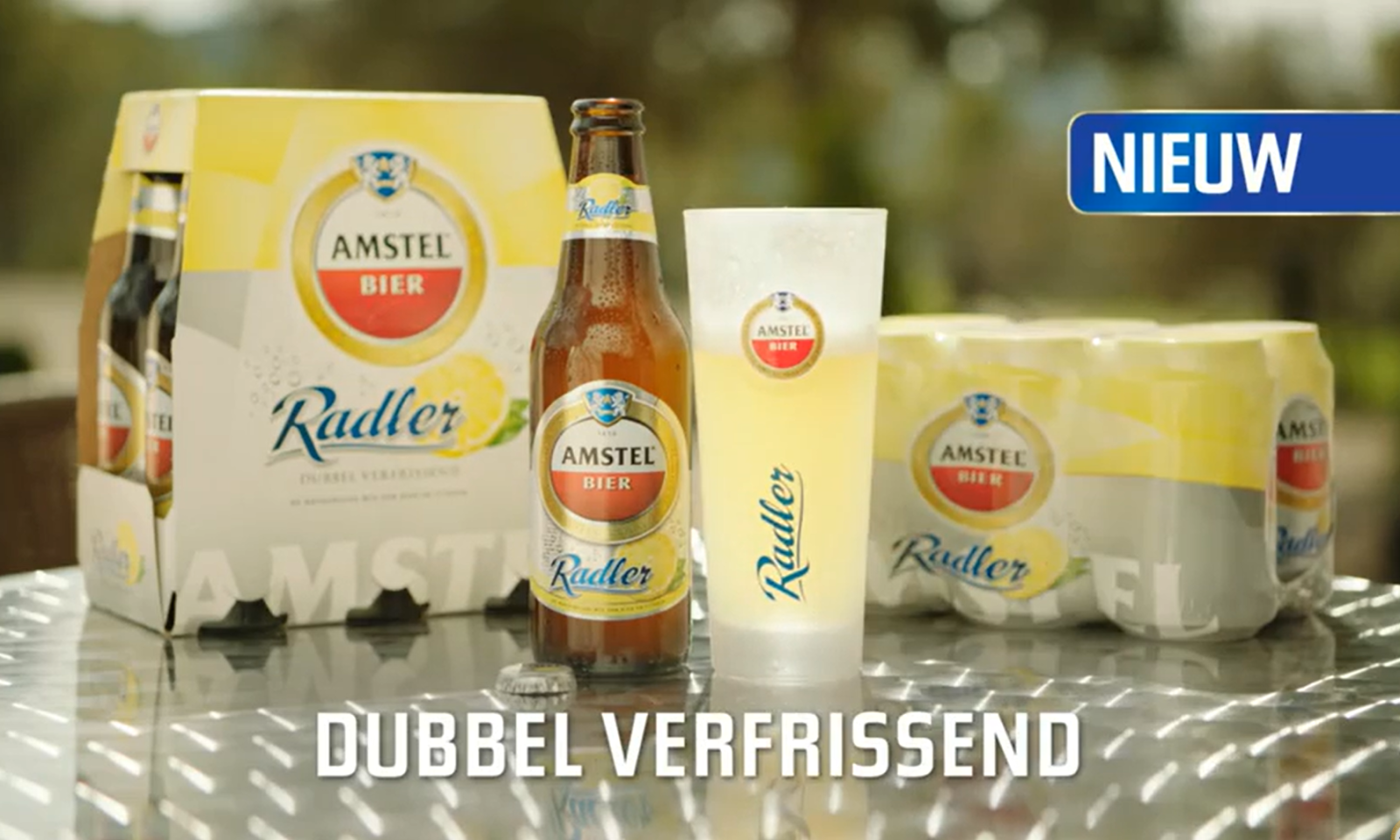 Amstel Radler fles, glas en verpakking op een tafel buiten.