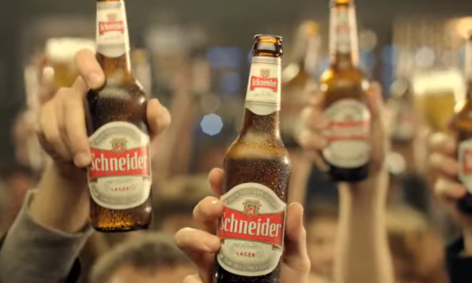 Handen die Schneider bierflessen omhoog houden, met een drukke menigte op de achtergrond.