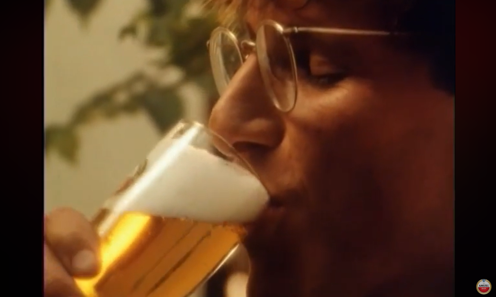 Close-up van een persoon met bril die een glas bier drinkt.
