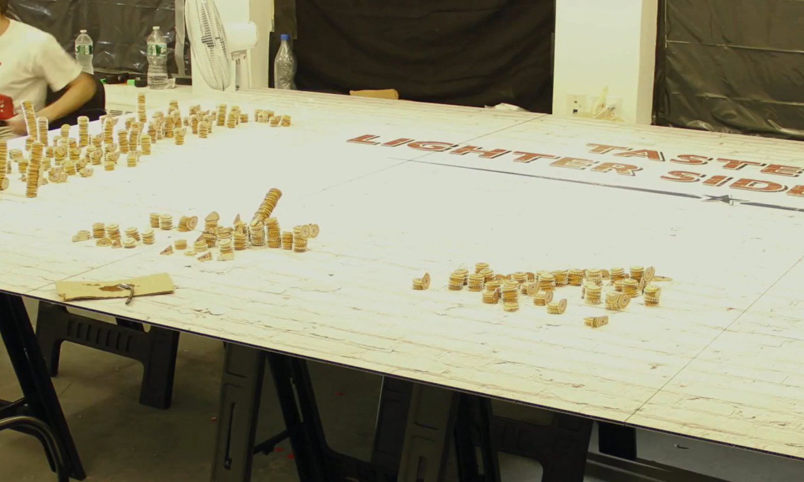 Een tafel bedekt met schaduwkunst gemaakt van gestapelde koekjes naast tekst in het midden.