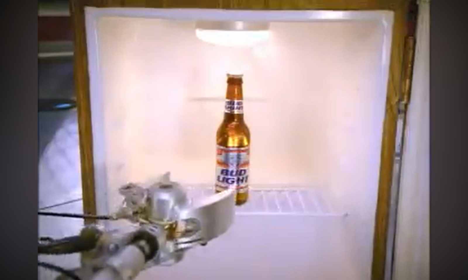 Robotarm pakt een fles bier uit een lege koelkast.
