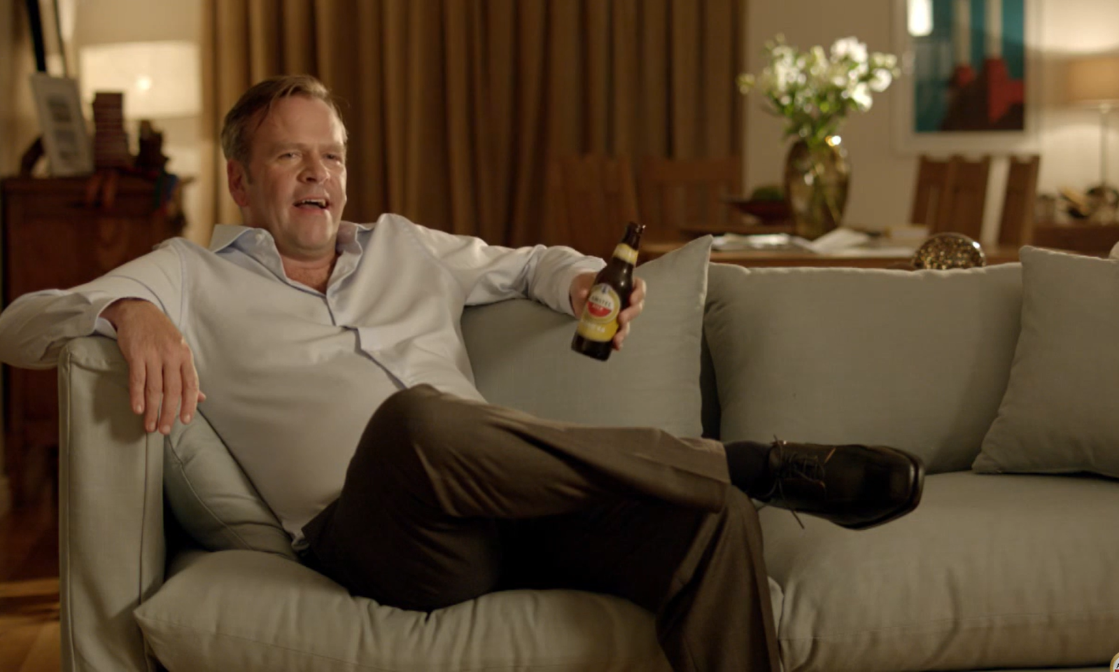 Man zit ontspannen op een bank met een Amstel Blond 4.0 flesje in zijn hand.