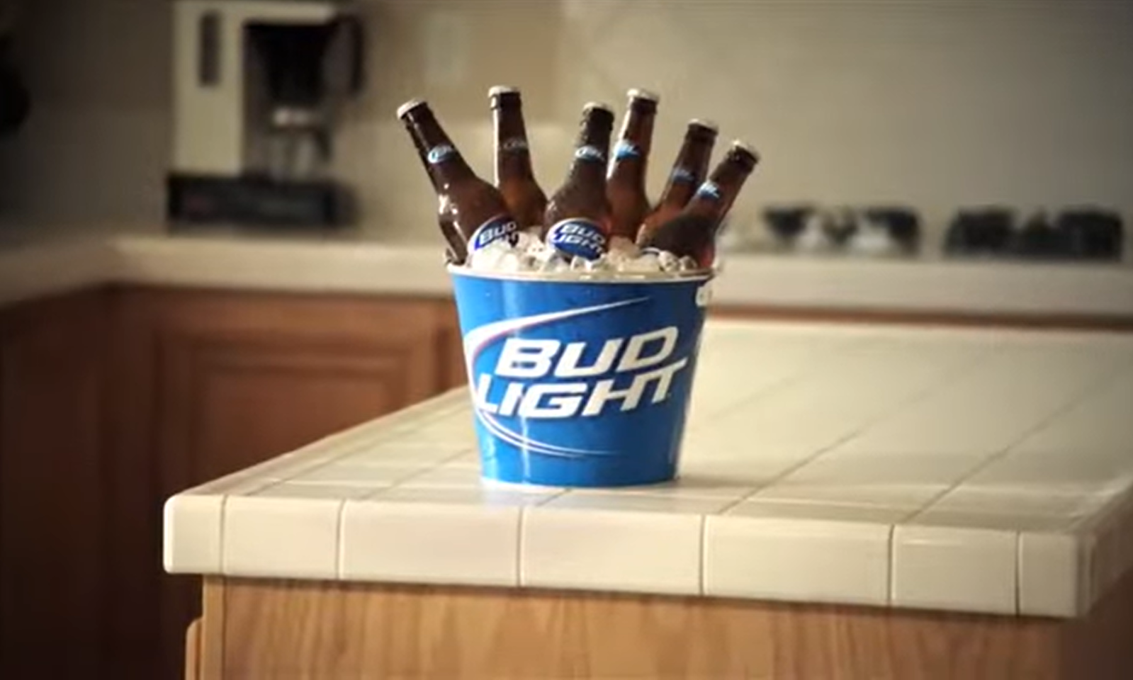 Emmer met Bud Light bier op keukentafel met zes flesjes.