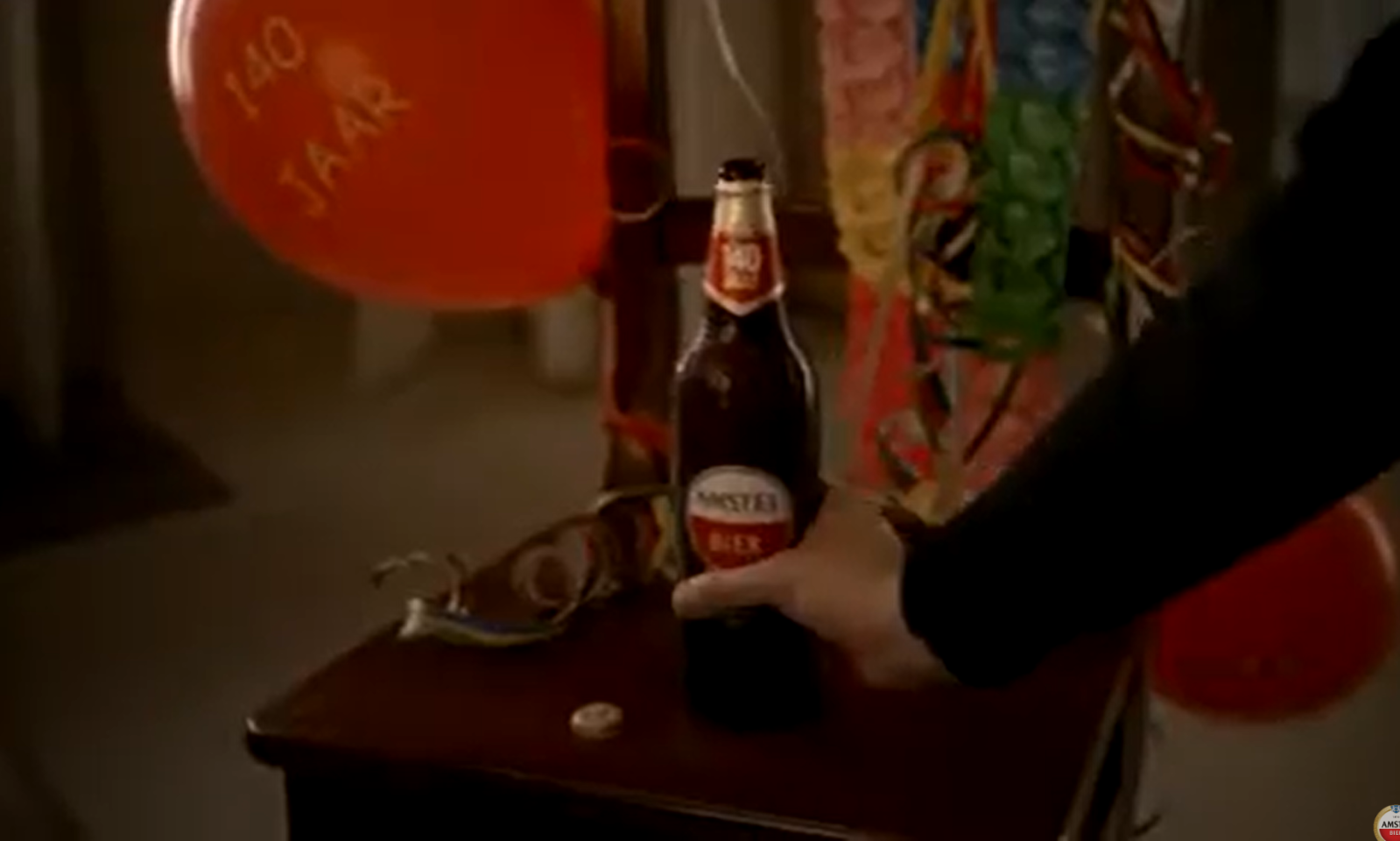 Fles Amstel bier naast rode ballon met '140 jaar' tekst.