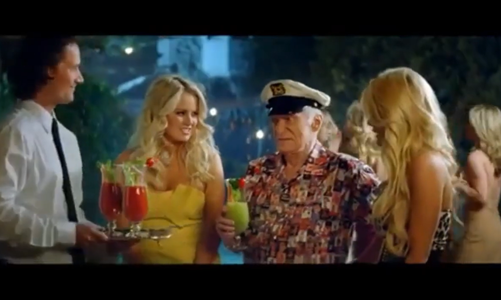 Mannen en vrouwen in felgekleurde kleding met drankjes tijdens een avondfeest.