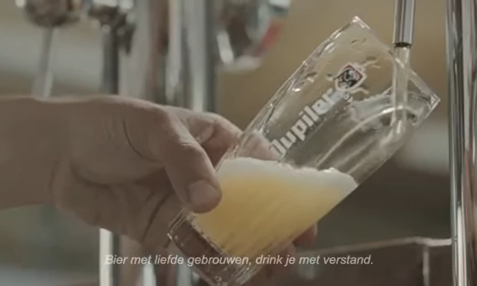 Hand tapt glas bier met schuimkraag naast biertap.