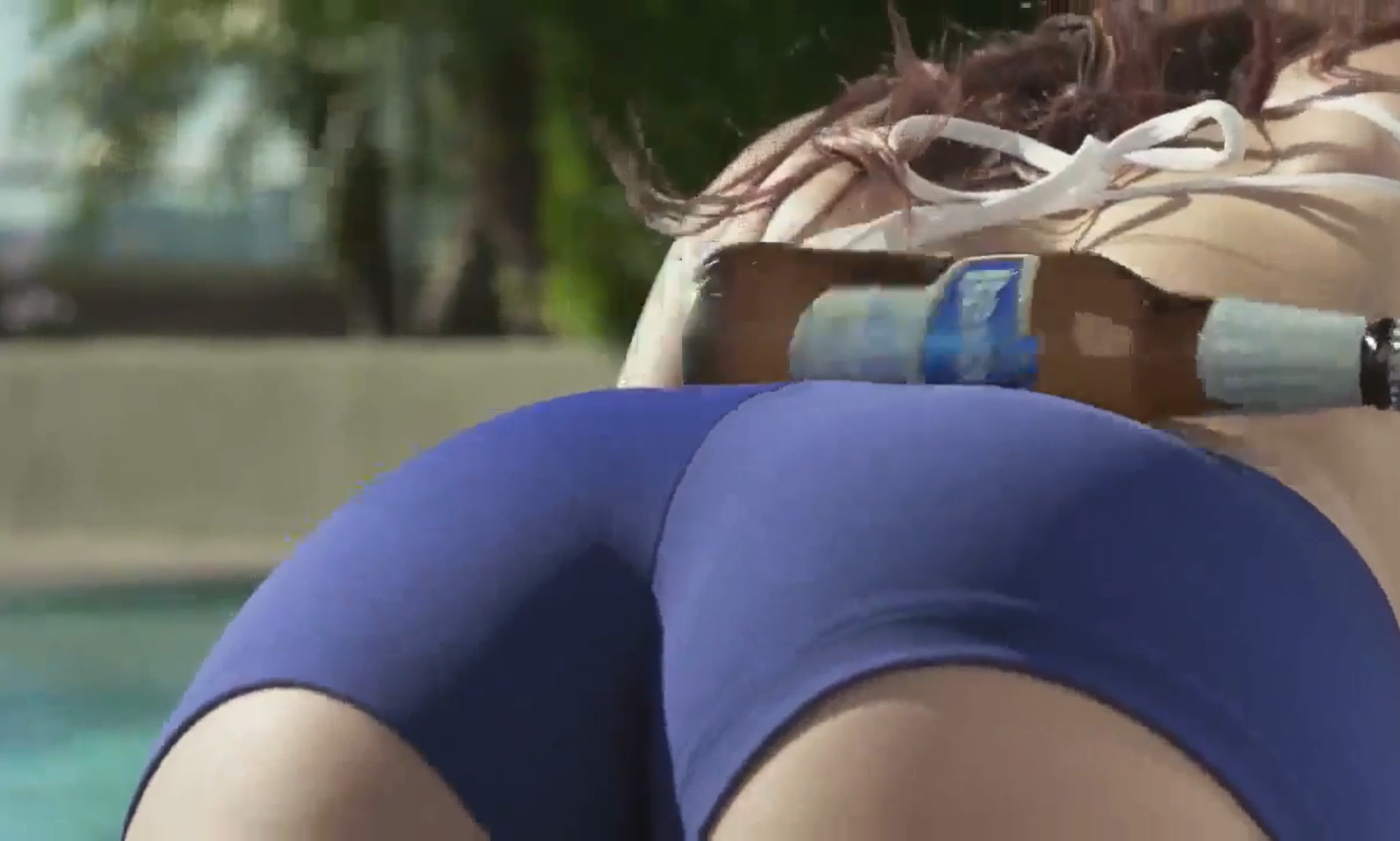 Vrouw ligt in bikini met bierflesje op rug bij zwembad