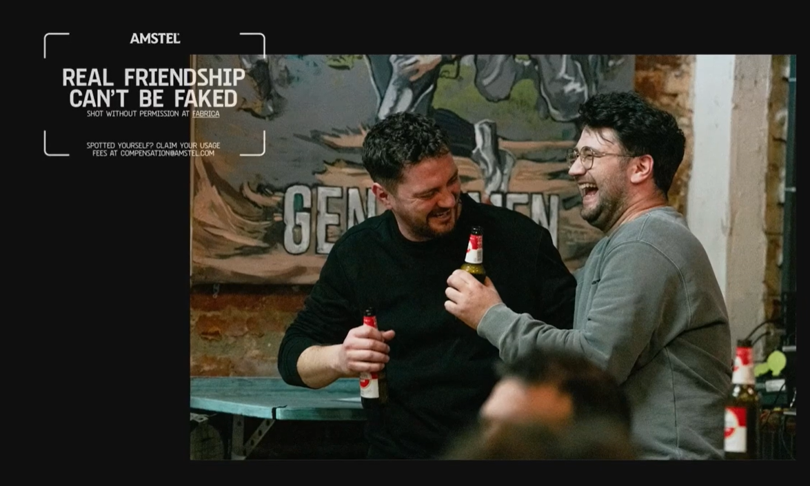 Twee vrienden lachen samen terwijl ze Amstel bier drinken in een gezellige bar.