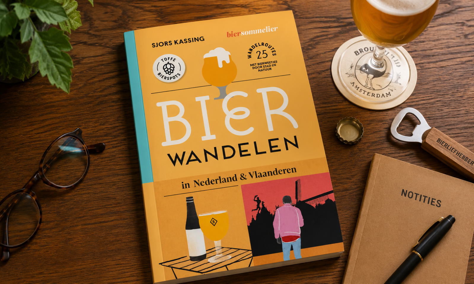 Boek Bierwandelen op houten tafel met glas bier, notitieboek, pen, bril en flesopener.