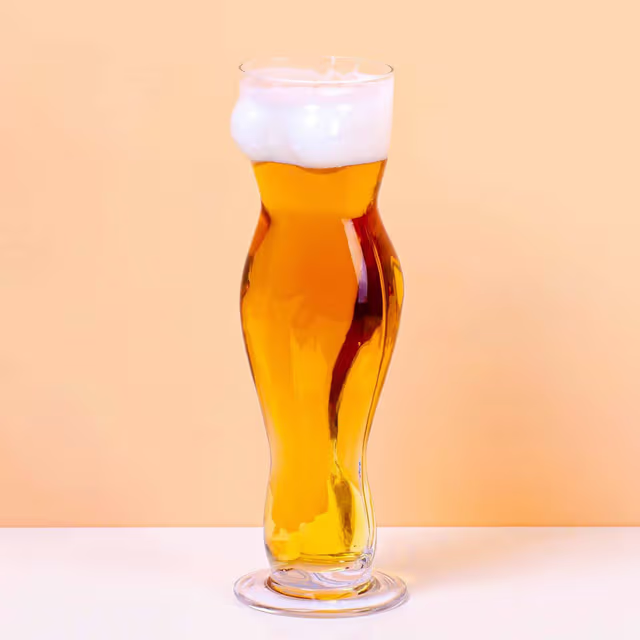 Bierglas in de vorm van een vrouwentorso met goudkleurig bier en schuimkraag op lichte achtergrond.