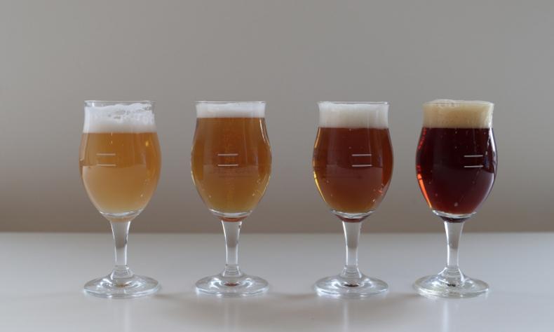 vier glazen bier met verschillende bierstijlen op een rij